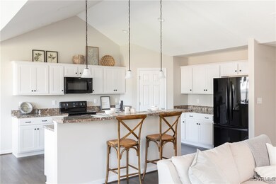 Kitchen featuring dark stone counters, black appli