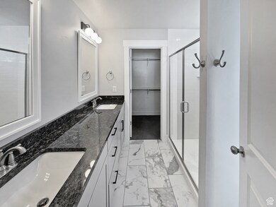 Full bath featuring marble finish floor, a sink, a walk in closet, and a shower stall