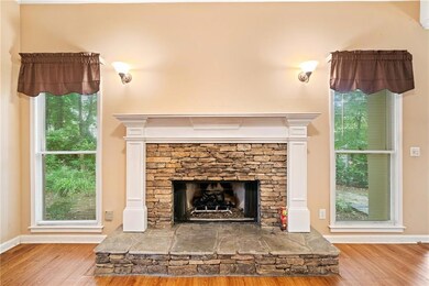 Detailed view of wood finished floors, a stone fireplace, and baseboards