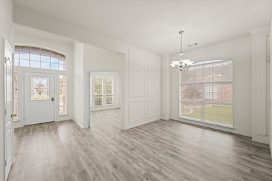 Foyer with light wood-type flooring and a chandelier
