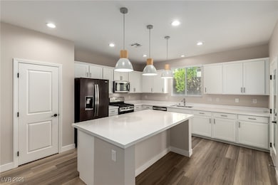 Kitchen with white cabinets, decorative light fixtures, appliances with stainless steel finishes, recessed lighting, and dark wood-style flooring
