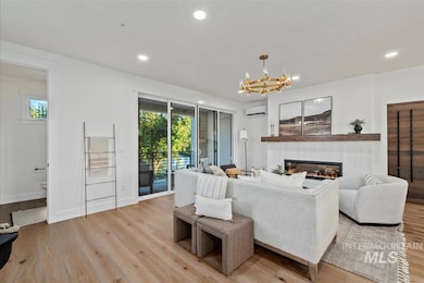 Living room featuring light wood-type flooring, a fireplace, recessed lighting, a chandelier, and an AC wall unit