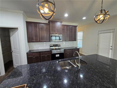Kitchen featuring stainless steel appliances, a sink, a chandelier, ornamental molding, and tasteful backsplash