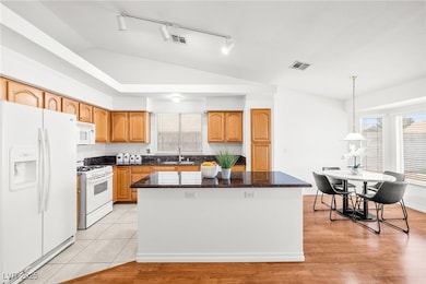Kitchen featuring white appliances, vaulted ceilin