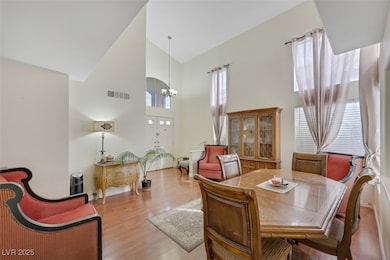 Dining space with high vaulted ceiling, a chandelier, and wood finished floors