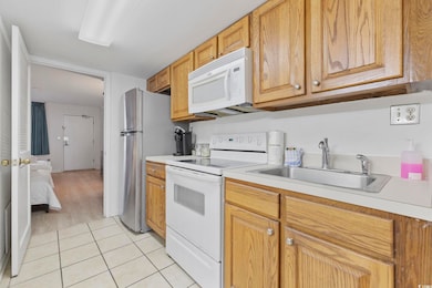 Kitchen with white appliances, sink, and light til