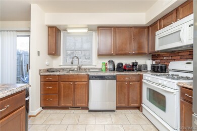 Kitchen with white appliances, light tile flooring, light stone countertops, and sink