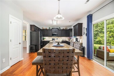 Kitchen with stainless steel microwave, freestanding refrigerator, a breakfast bar area, light wood-style floors, and decorative backsplash