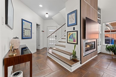 Entrance foyer with stairs, a glass covered firep