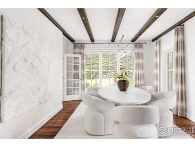 A formal dining room impresses with soaring windows, wood-beamed ceilings, and an ornate pocket door.