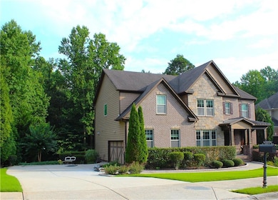 Craftsman inspired home featuring a garage, stone siding, driveway, and brick siding