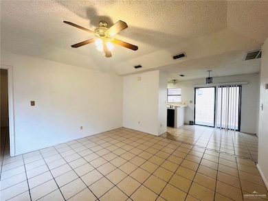 Tiled empty room featuring ceiling fan and a textured ceiling