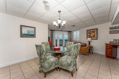Dining area with light tile patterned floors, a drop ceiling, and an inviting chandelier