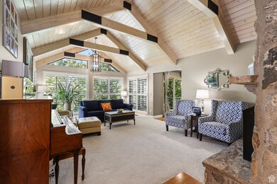 Give me a cozy mountain-modern living room with big windows, wood beams, and sunlight everywhere.