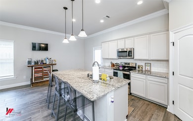 Kitchen featuring stainless steel appliances, crown molding, decorative backsplash, dark wood-type flooring, and light stone counters