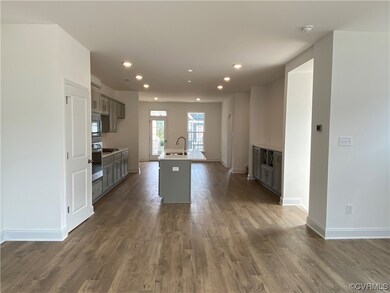 Kitchen with dark hardwood floors, appliances with stainless steel finishes, light countertops, and white cabinets