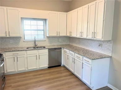 Kitchen with white cabinetry, tasteful backsplash, light stone countertops, and appliances with stainless steel finishes