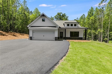 Modern inspired farmhouse with asphalt driveway, an attached garage, stone siding, a shingled roof, and a front yard