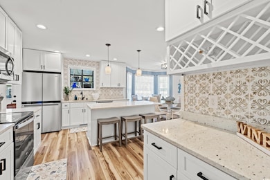 Kitchen with a sink, backsplash, white cabinetry, 