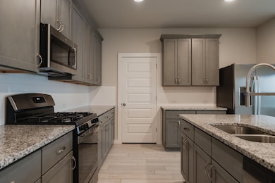 Kitchen with light stone countertops, appliances 