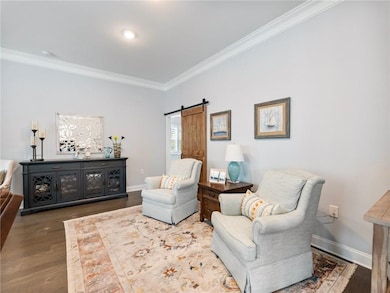 Sitting room featuring ornamental molding, wood finished floors, and a barn door