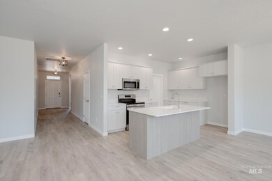 Kitchen with appliances with stainless steel finishes, light wood-style floors, white cabinetry, a kitchen island with sink, and recessed lighting