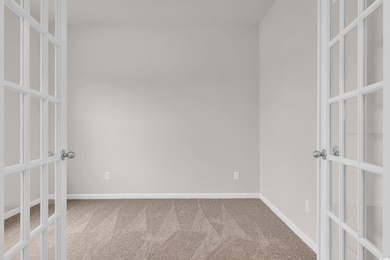 Carpeted spare room with french doors and baseboar