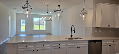 Kitchen featuring stainless steel dishwasher, a sink, white cabinetry, and light countertops