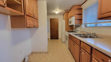 Kitchen with open shelves, white appliances, light countertops, and brown cabinets