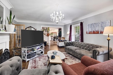 Living area featuring a chandelier, wood finished floors, crown molding, and a fireplace