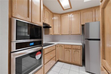 Kitchen featuring light brown cabinetry, appliances with stainless steel finishes, tasteful backsplash, and light tile patterned flooring