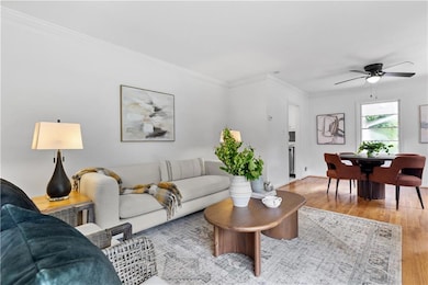 Living area with ceiling fan, light wood-style floors, and crown molding