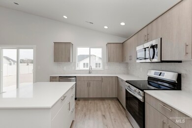 Kitchen with appliances with stainless steel finishes, lofted ceiling, tasteful backsplash, light wood-style floors, and recessed lighting