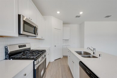 Kitchen featuring white cabinetry, light hardwood 