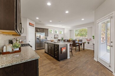 Kitchen with dark brown cabinetry, light stone co