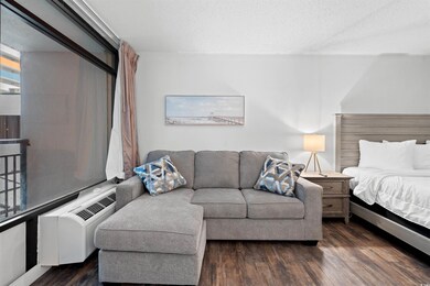 Bedroom featuring wood finished floors, a textured ceiling, and a wall mounted air conditioner