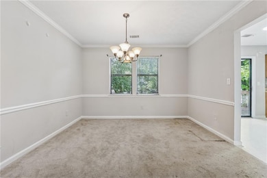 Carpeted empty room featuring a chandelier, crown 