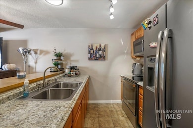 Kitchen featuring appliances with stainless steel finishes, brown cabinets, and a textured ceiling