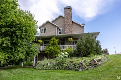 Back of property with a yard, a porch, stone siding, and a chimney