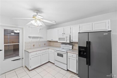 Kitchen featuring stainless steel refrigerator with ice dispenser, range with electric cooktop, tasteful backsplash, and white cabinetry