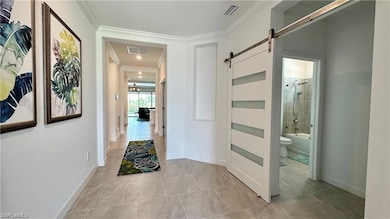 Hall featuring a barn door, crown molding, and lig