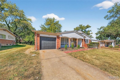 Ranch-style home with a front yard, an attached garage, concrete driveway, and brick siding