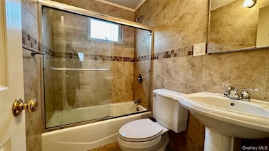 Bathroom with tile walls and bath / shower combo with glass door