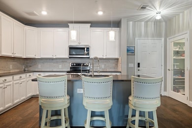 Kitchen with dark wood-style floors, stainless ste