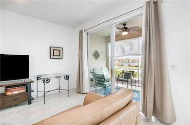 Living area with a ceiling fan, light tile patterned floors, and baseboards