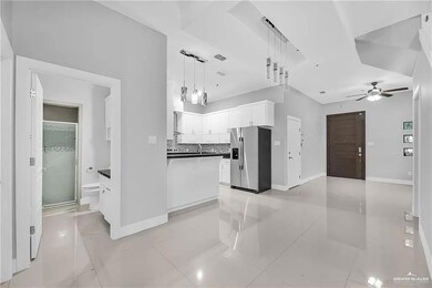 Kitchen featuring white cabinets, stainless steel refrigerator with ice dispenser, decorative light fixtures, light tile floors, and ceiling fan
