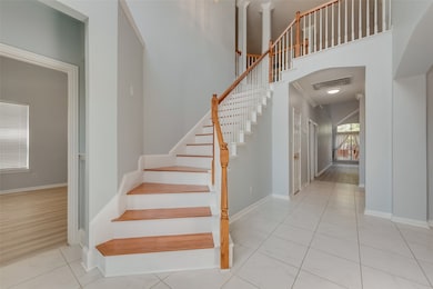 Stairway featuring tile patterned flooring, arched walkways, and a high ceiling