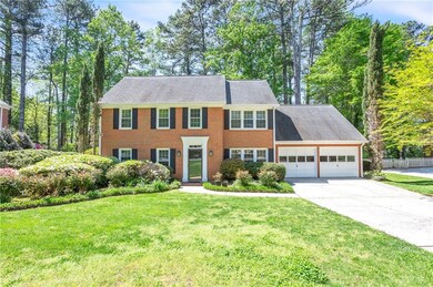 Colonial home featuring a garage, a front yard, concrete driveway, and fence