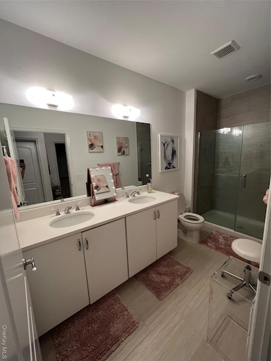 Bathroom featuring a shower stall and double vanity