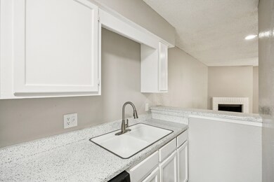Kitchen with white cabinetry, a textured ceiling, and light stone countertops